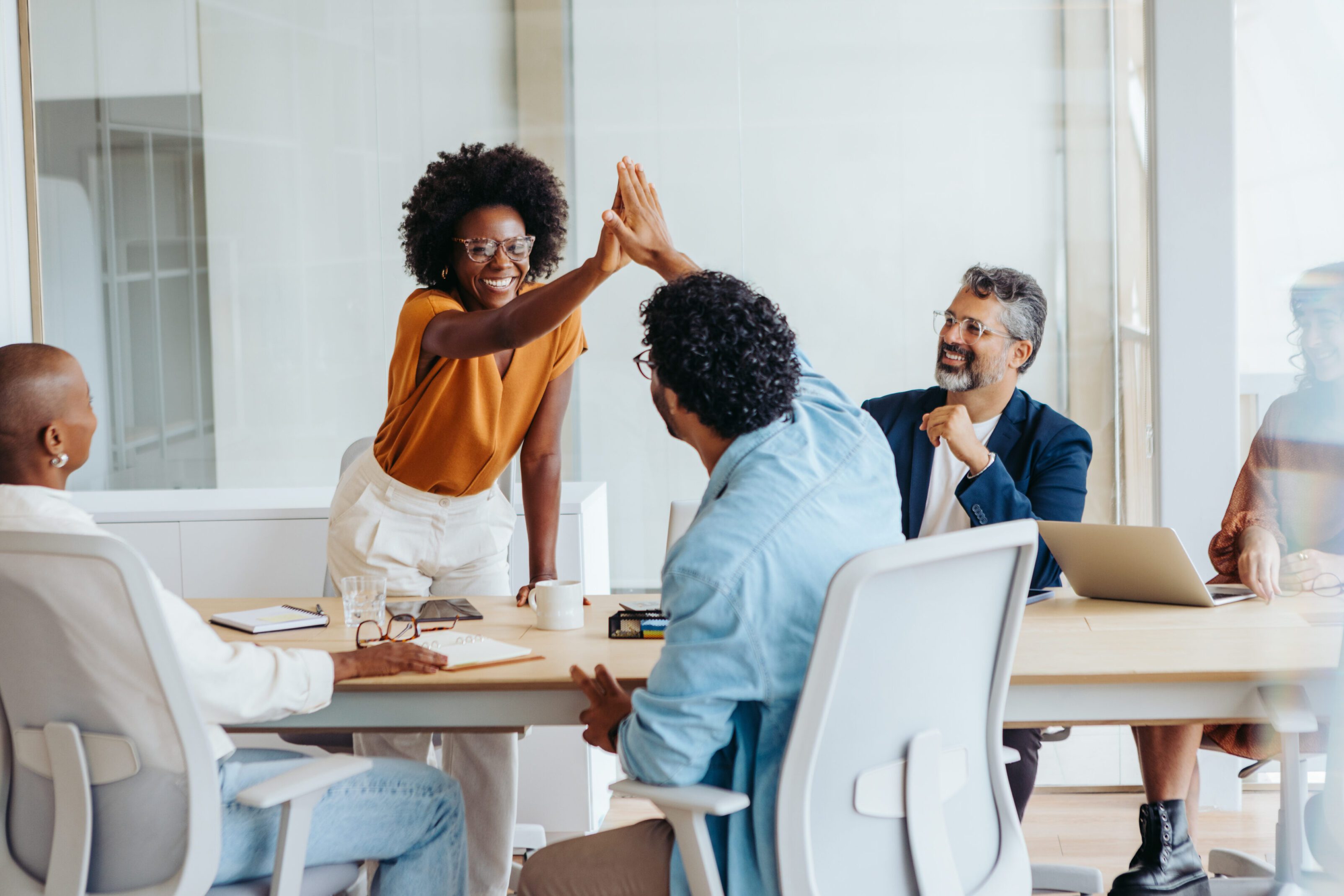 Professionals celebrate their achievements with a high five, promoting teamwork and success in this creative startup environment. Business people collaborating in a vibrant office setting.