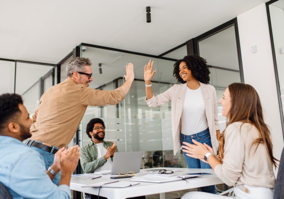 Team celebrating with high-fives in office.